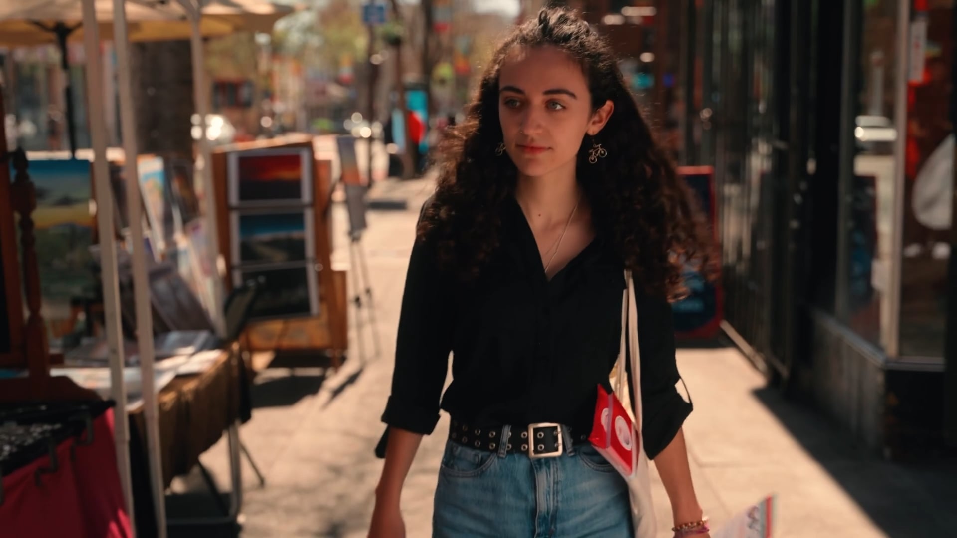 Young woman walking down a Berkeley street lined with sidewalk art vendors