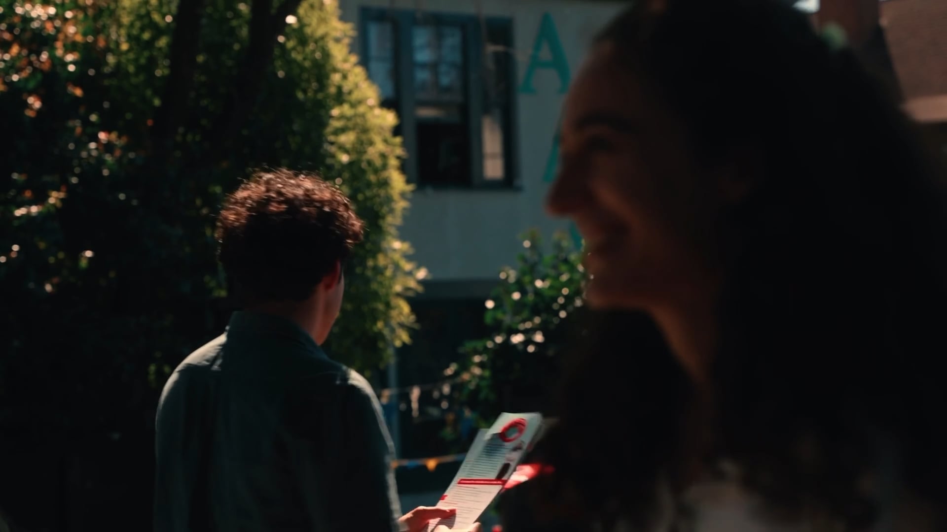 Two people talking outdoors, one holding a campaign flyer
