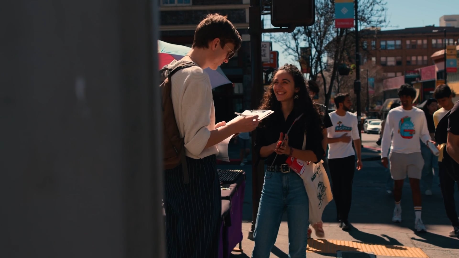 Volunteer with a clipboard talking to a smiling voter on a city sidewalk