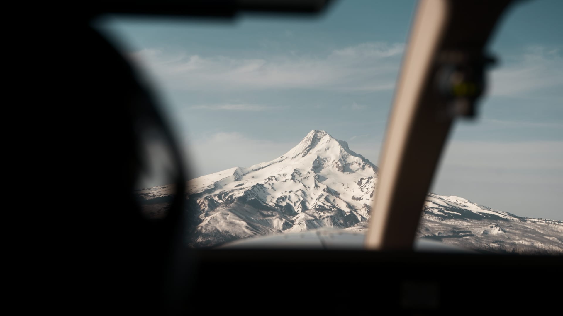 View through an aircraft window of a snow-covered volcanic peak