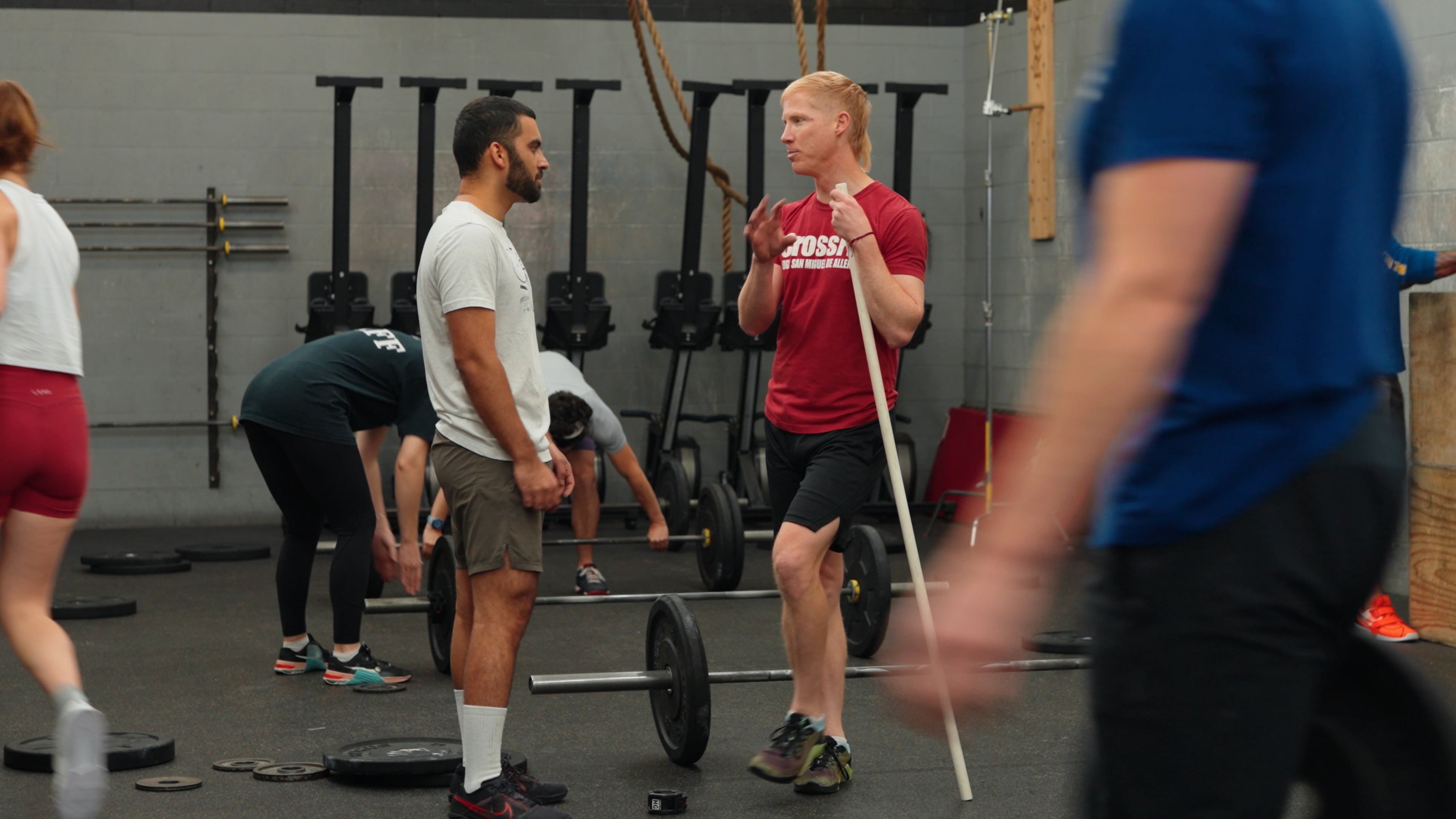 Coach talking with a member near the barbells during a class