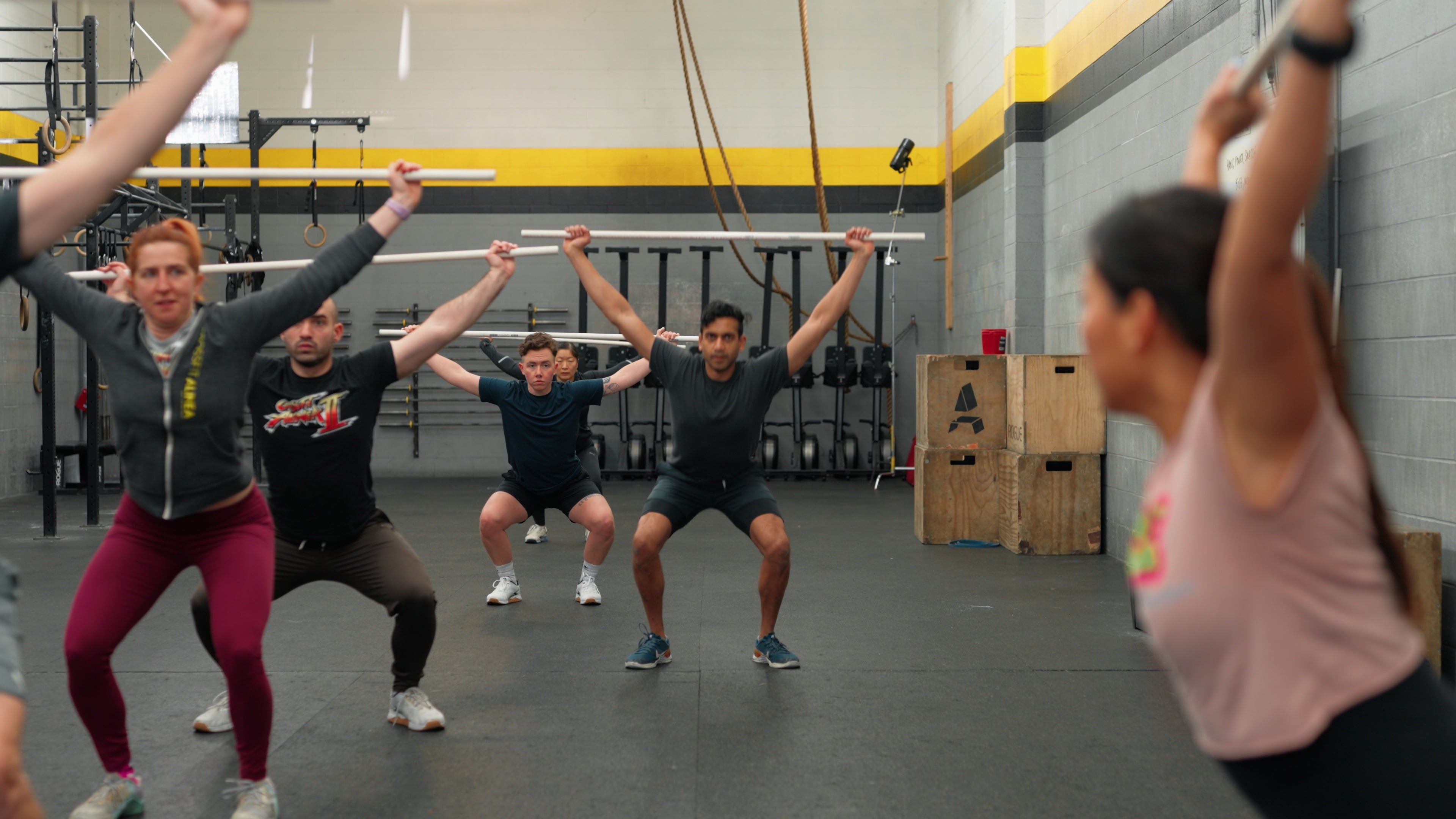 Group of members doing overhead squats with PVC pipes