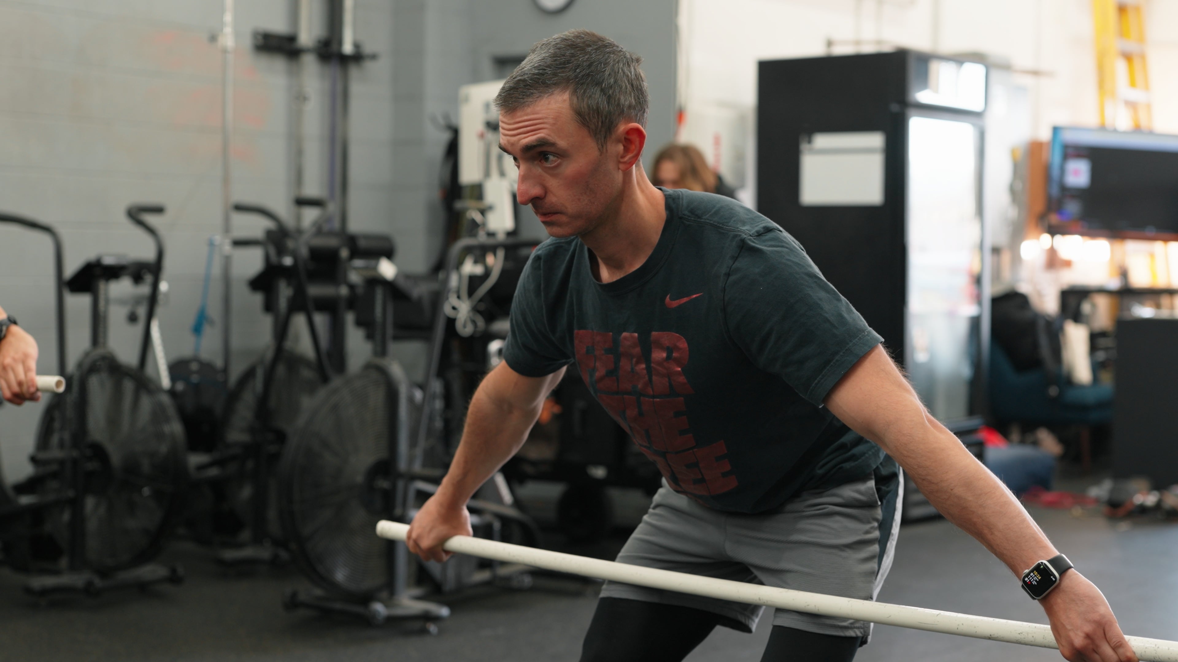 Member doing a hip-hinge stretch with a PVC bar