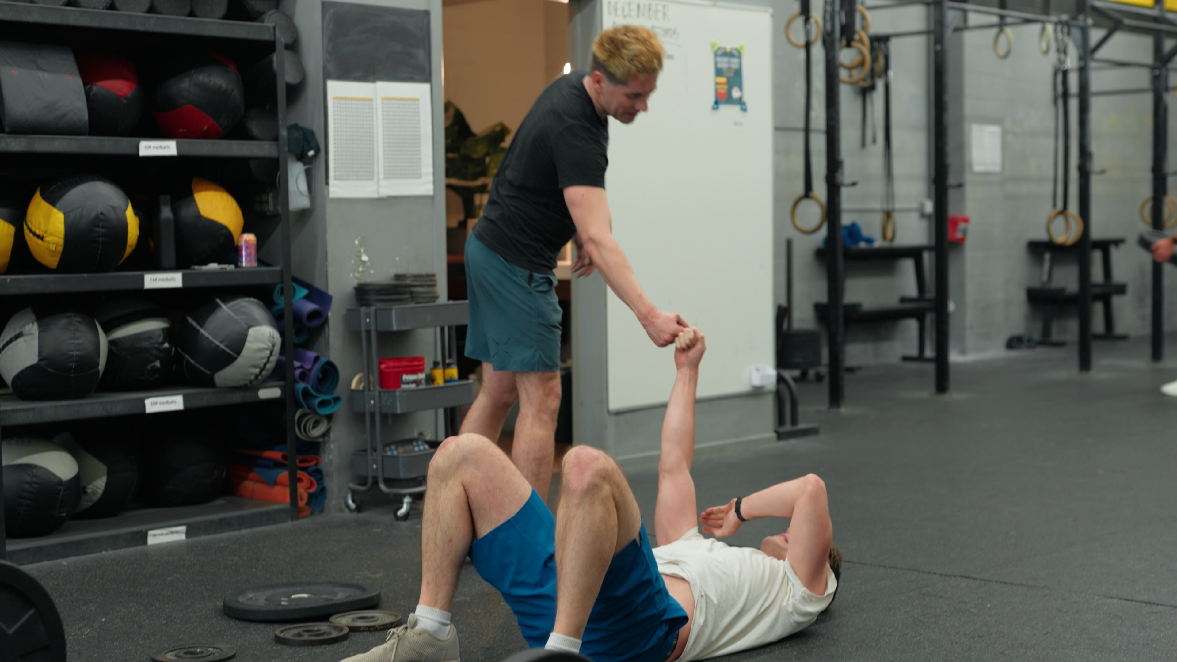 Coach helping a member up off the floor with a fist-bump grip