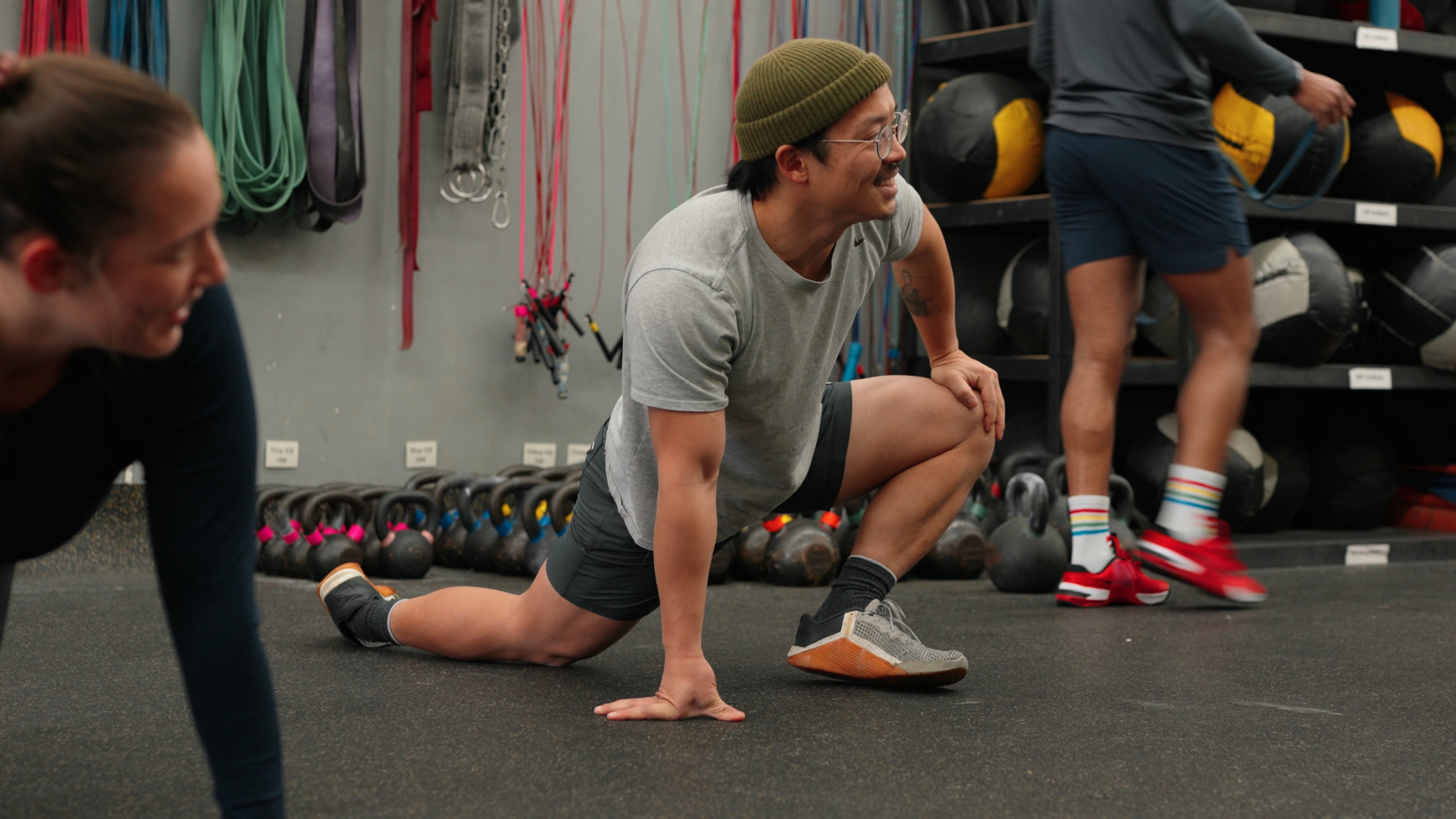 Member in a beanie smiling while stretching in a lunge position