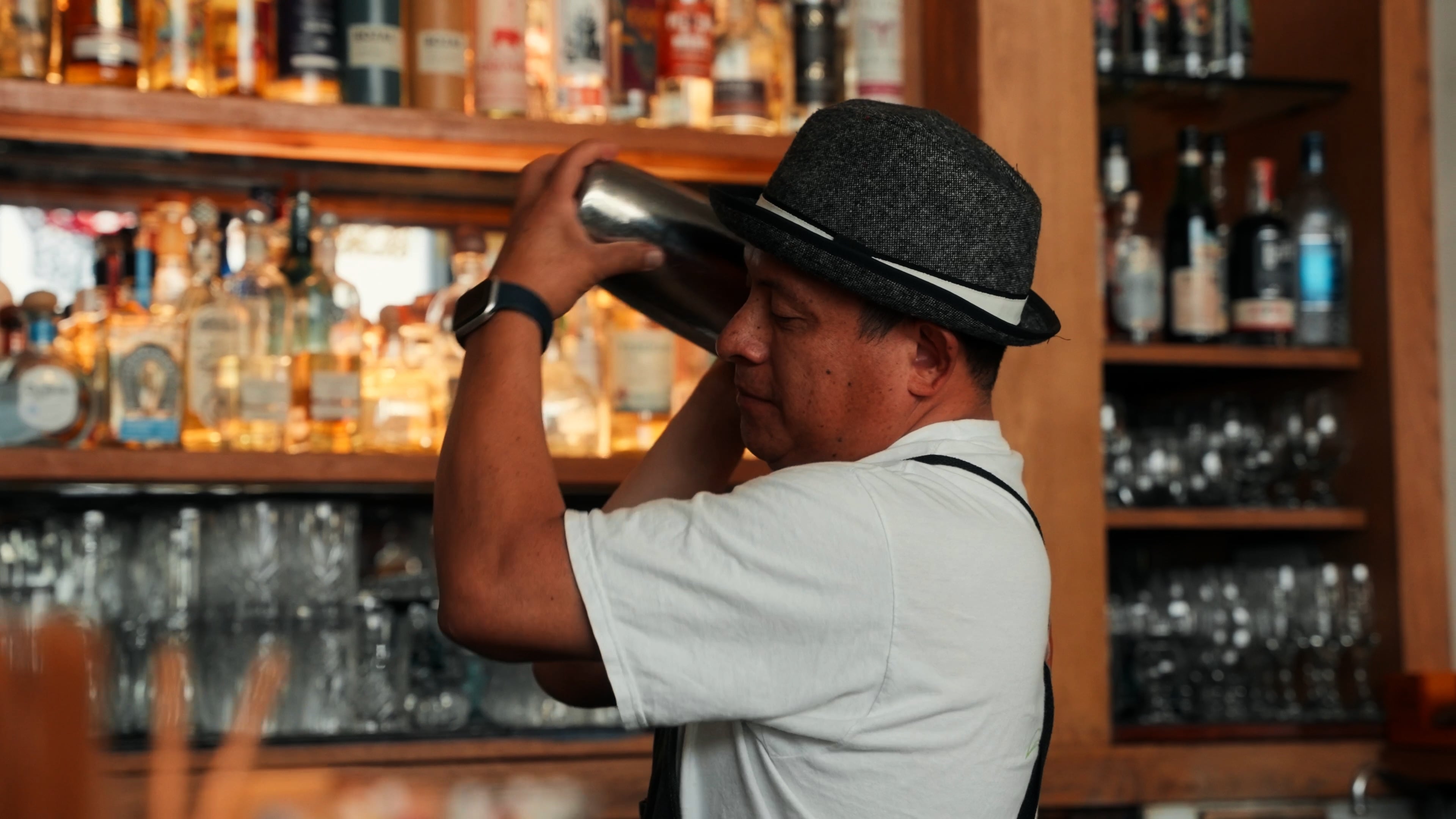 Bartender in a fedora shaking a cocktail behind the bar at Matador SF