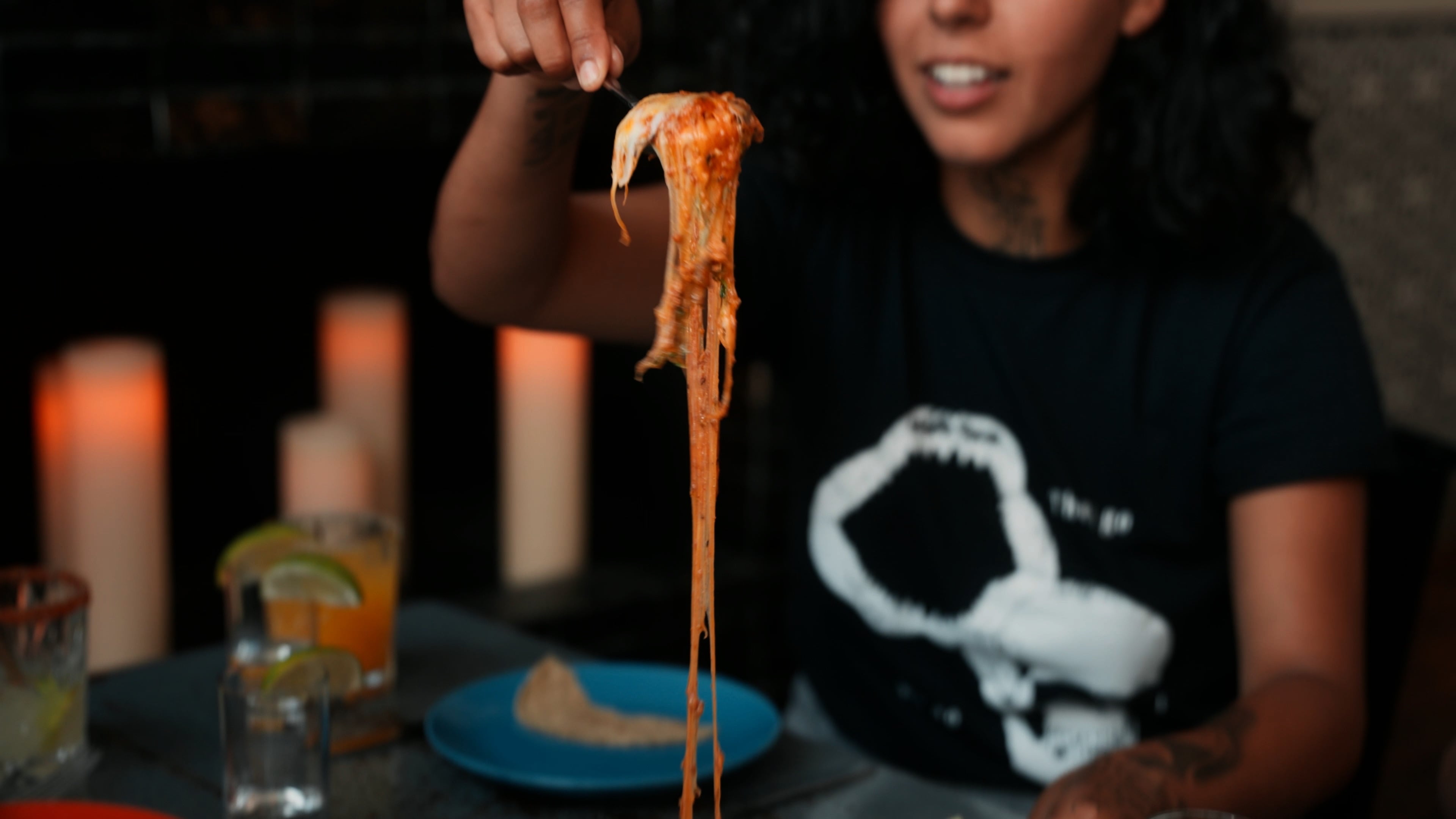 Diner lifting a forkful of cheese-topped food with a long cheese pull